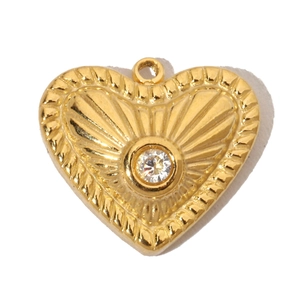 Macro shot of a vintage gold heart pendant with radial patterns and a clear zircon stone