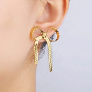 Detail of elegant gold bow pendant earring with snake chain tassel on model