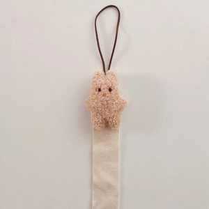 Detail view of beige plush bear hair accessory organizer with cotton herringbone strap