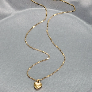 Elegant gold heart pendant necklace on grey silk background featuring unique chain links