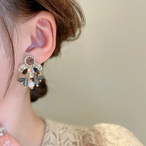 Close-up of vintage gold tassel earrings with purple stones and pearls worn by a model