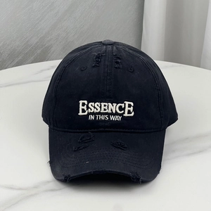 Close-up of distressed ripped details and white embroidered text on black cotton baseball cap