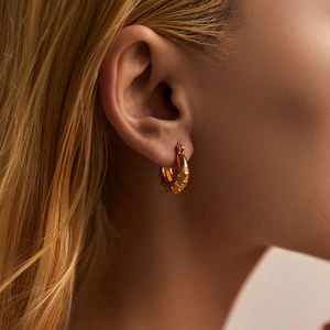 Detailed close-up of gold-plated textured hoop earrings with granular vintage craftsmanship