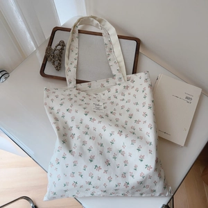 Detail of floral canvas tote bag with book and hair clip in a lifestyle setting