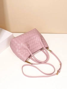 Pink woven leather tote bag with dual handles and gold hardware on white pedestal