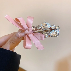 Détail d'une pince à cheveux avec nœud en satin rose et strass en cristal brillant