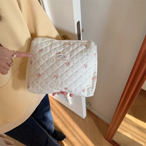 Close-up of floral quilted makeup bag with red flower pattern and top zipper detail