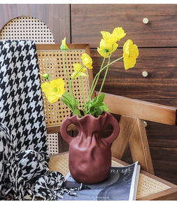 Detail der terrakottafarbenen Keramikvase mit Wellentextur und gelben Mohnblumen