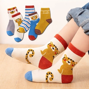 Five pack of cotton kids crew socks with tiger patterns and stripes on wood background