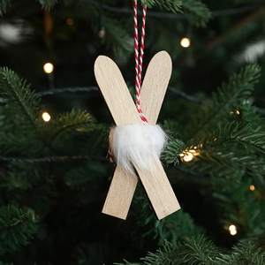 Nordic red wooden sled Christmas ornament with white fur hanging on a festive tree branch
