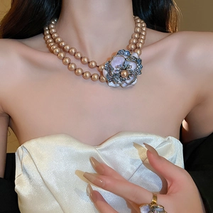 Close-up of double-layer champagne pearl necklace with floral enamel pendants