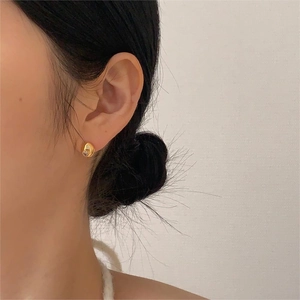 Close-up of irregular gold plated stud earring with zircon on model's ear