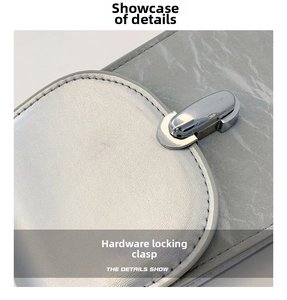 Close-up of shiny silver metal buckle on grey textured leather crossbody bag detail