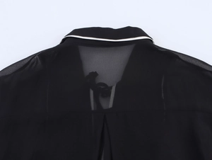 Vue détaillée du dos d'une robe en mousseline noire avec liseré blanc et détails plissés