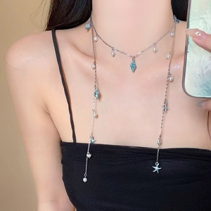 Detailed view of ocean theme necklace featuring blue starfish, conch pendants and white pearls
