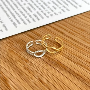Detail of adjustable silver and gold geometric rings on a minimalist wooden and magazine background