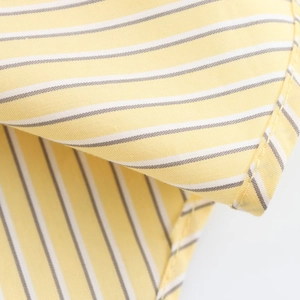 Close-up of yellow and white striped cotton fabric texture with neat hemmed stitching