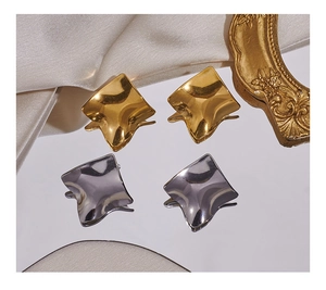 Detailansicht quadratischer Metallohrstecker mit Wellenstruktur in Gold und Silber