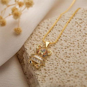 Detail view of a gold bear necklace with colorful rhinestones on a natural stone background