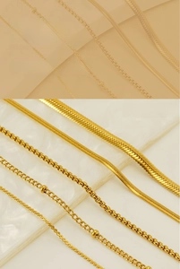 Detailed macro view of 18K gold plated snake and curb chain necklaces on stone background