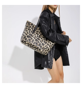 Fashionable leopard print tote bag with black straps carried by a model in leather jacket