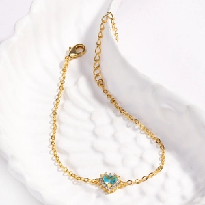 Bracelet coeur doré élégant orné d'un zircon bleu sur un plateau en coquillage