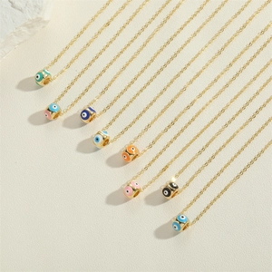 Golden evil eye enamel bead necklaces in eight vibrant colors on a textured surface