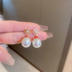 Detail of Christmas tree earring with gold snowflake, red accent, and white pearl drop