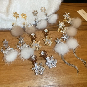 Detail of Christmas reindeer earrings with snowflakes, rhinestones, and white plush balls