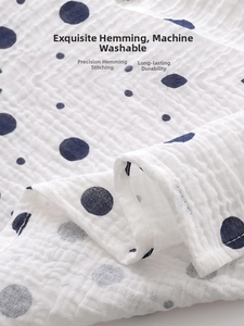 Macro detail of breathable cotton muslin baby towel with blue polka dots and reinforced edges