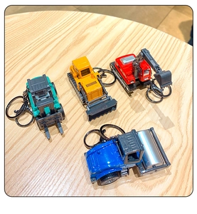 Miniature construction vehicle keychains in yellow, red, blue, and green on wooden table