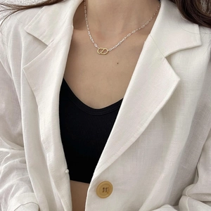 Detailed view of elegant gold CD pendant on silver chain worn with a white linen suit