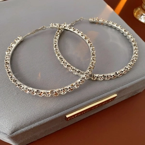 Macro shot of silver-tone hoop earrings with crystals on a grey velvet jewelry box