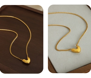 Vue macro détaillée du pendentif cœur doré avec finition polie miroir sur une chaîne fine