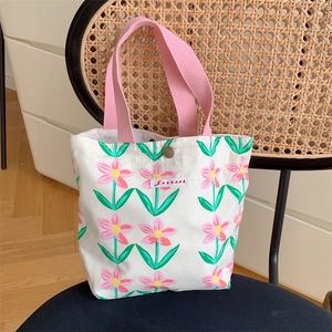 Dettaglio della borsa da pranzo in tela floreale con manico rosa e bottone a scatto