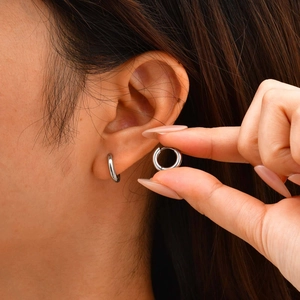 Close-up of minimalist silver stainless steel hoop earring worn on a female ear model