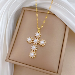 Detail shot of golden cross pendant with white pearls and sparkling pavé crystals