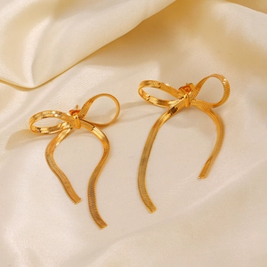 Boucles d'oreilles nœud en acier doré 18K sur fond de soie beige élégant