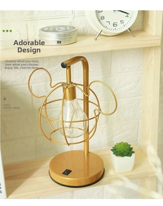 Close-up of golden mouse-shaped LED table lamp with retro bulb on a wooden shelf