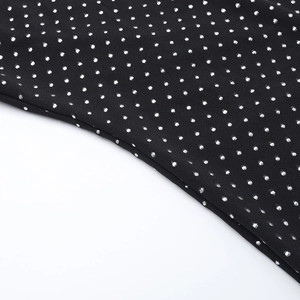Detailed close-up of black fabric with metallic silver polka dots on wide-leg jumpsuit