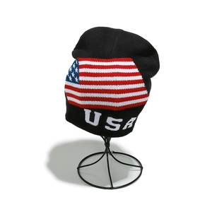 Detail of USA knit beanie featuring flag jacquard pattern and folded cuff on metal stand