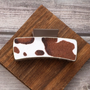 Cow print leather large hair claw clip with brown matte base on wooden display