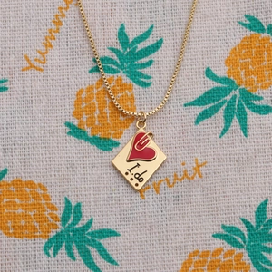 Collier plaqué or avec pendentif losange I DO et cœur sur tissu à motifs d'ananas