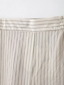 Detail of elastic waistband and vertical stripes on beige casual trousers with stitching