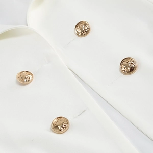 Detail of white suit fabric with premium golden double-breasted embossed metal buttons
