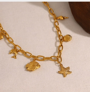 Detailed close-up of 18K gold-plated ocean charms including starfish and shells on a chain