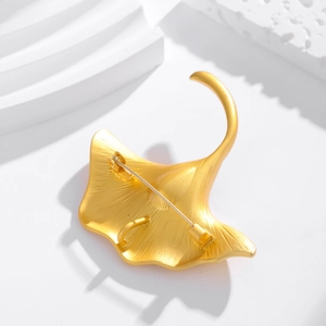 Elegant gold ginkgo leaf brooch and pendant with vintage finish on a white background