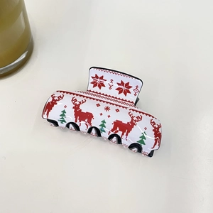 Detailed view of a white Christmas hair claw clip with red reindeer and green tree patterns