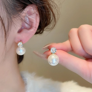 Close-up of elegant gold pearl earring with cubic zirconia on model ear for women