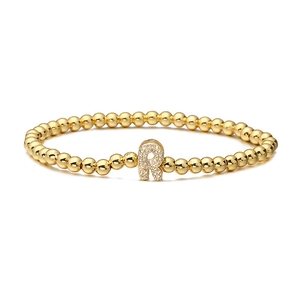 Detailed shot of golden beaded stretch bracelet featuring a micro-paved zircon letter R charm